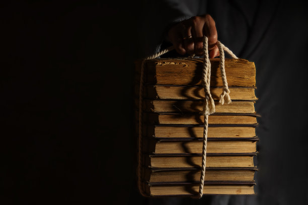 一只手会从黑暗中拉出一堆用绳子绑着的旧书图片下载