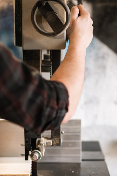 难以辨认的特写男木工工人双手使用磨床锯刨机，打开或控制面板上的阀门图片下载