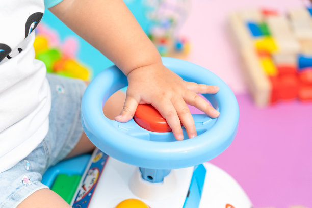 孩子按下位于玩具汽车方向盘上的红色信号按钮图片下载