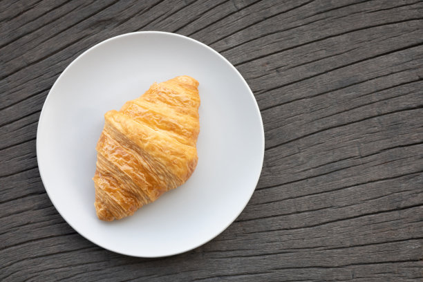 新鲜美味的早餐早晨与咖啡，食物羊角面包在早午餐盘，果酱在黑暗的垃圾木背景。大陆早餐捕捉在上面的桌面视图平躺。图片下载