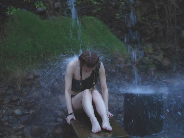 一名女子在户外的一条矿泉下洗澡。女人在户外喷水。户外矿产淋浴。Bluured形象图片下载