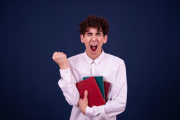 惊讶的年轻迷人的学生正在看书。图片下载