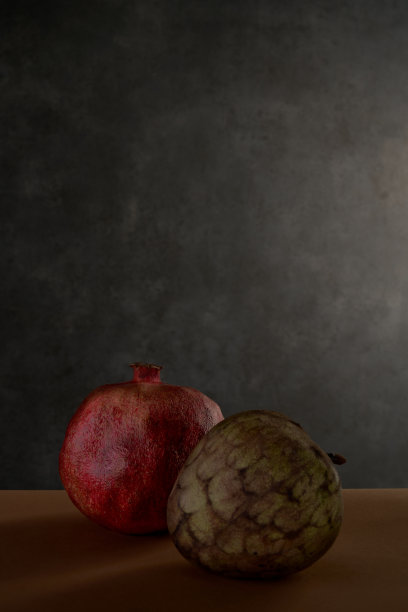 静物与番荔枝和石榴，黑暗的背景。图片下载