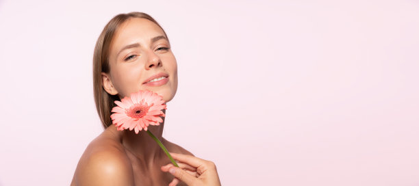 美丽的年轻女孩，有光泽的金发拿着花孤立在白色的背景。形状和线条，化妆品，自然美图片下载