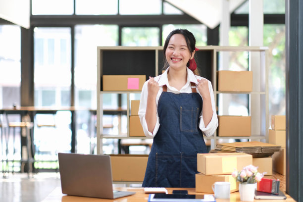 创业小企业企业家或自由职业的亚洲女性用笔记本电脑和盒子，年轻成功的亚洲女性用她的手举起，网上营销包装盒和快递，中小企业的概念。图片下载