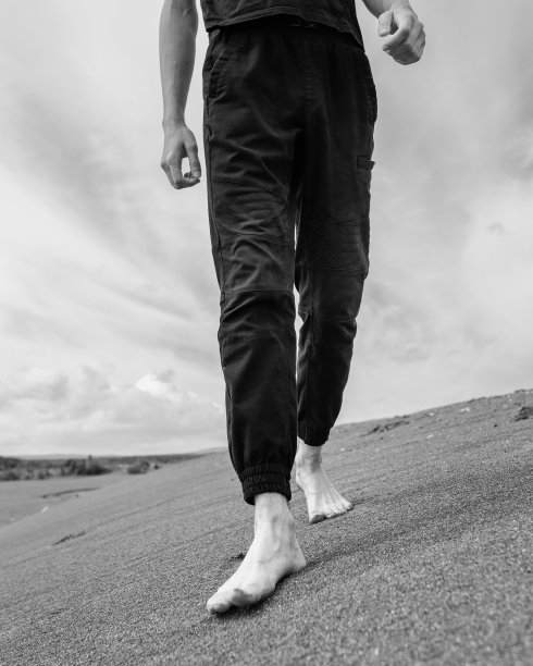 一个年轻人独自走在沙漠中的沙子上图片下载