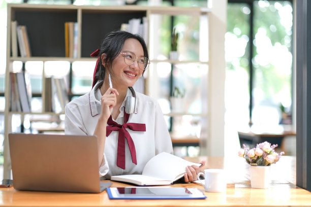 快乐的年轻亚洲女学生戴着耳机看着网络摄像头，看着摄像头，在虚拟会议或视频通话中交谈。图片下载
