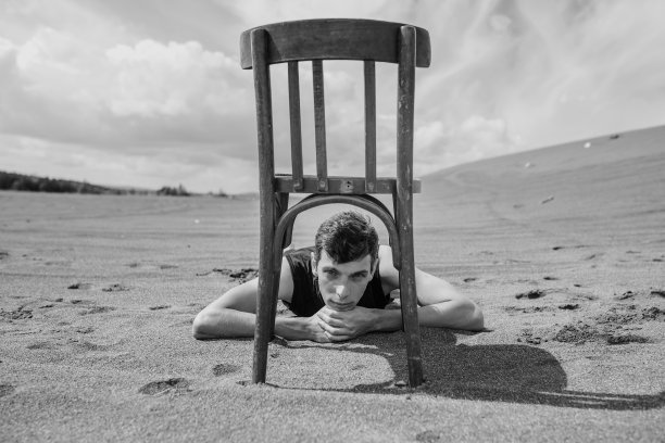 沙漠里躺在椅子下的人图片下载