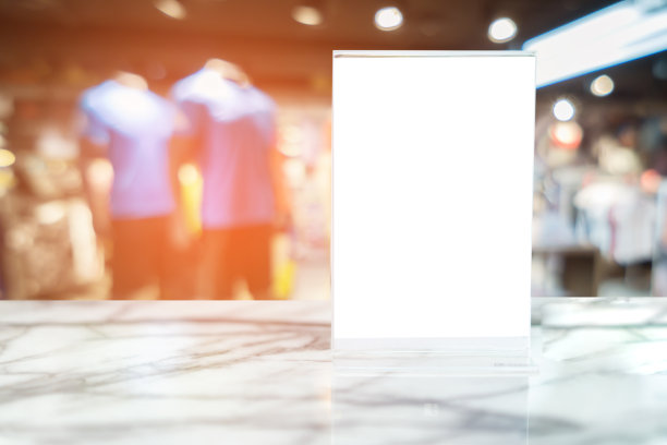 在酒吧餐厅的空白菜单框上贴上标签，在大理石桌子上的摊位上用白纸做小册子，亚克力帐篷卡片，模糊的背景可以插入顾客的文字。图片下载