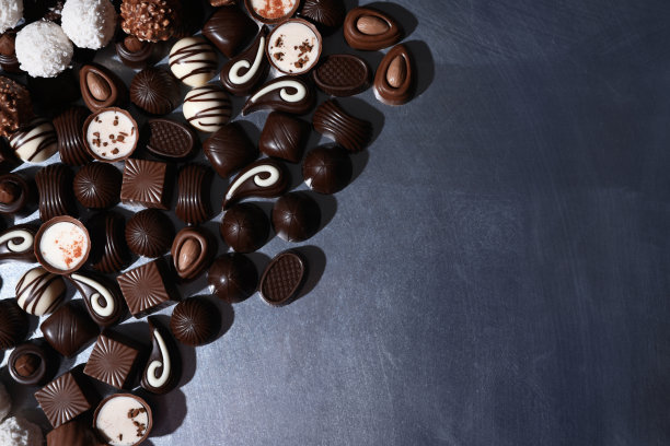 许多不同的美味巧克力糖果在金属表面，平铺。空间的文本图片下载