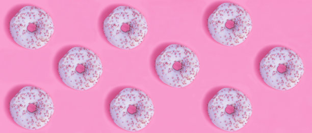 粉色背景上有粉色釉的甜甜圈。横幅。平的。图片下载