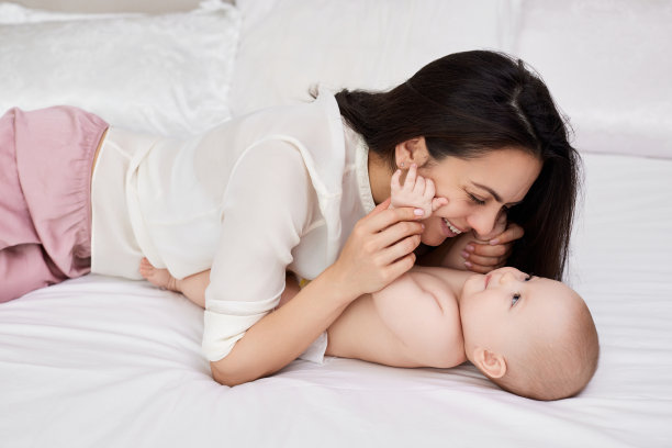 母亲在卧室里和她的女婴玩耍。图片下载