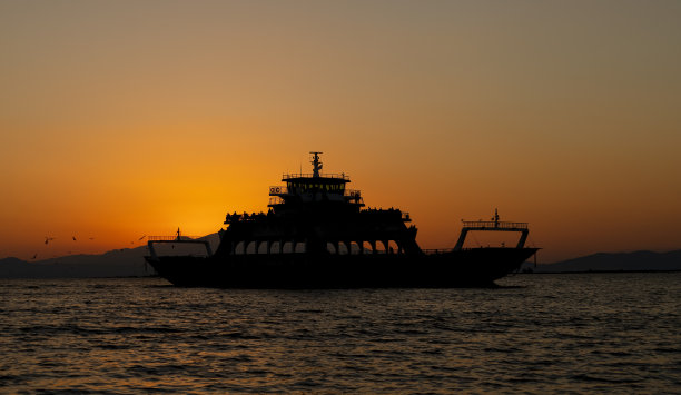 日落时海上渡船的剪影图片下载