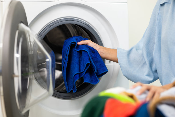 快乐美丽的家庭主妇打开洗衣机的前面，准备在周末把脏衣服放进洗衣机。清洗衣服的女人。图片下载