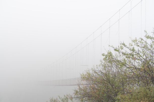 雾景在Khndzoresk悬索桥上的洞穴城市在山的岩石。亚美尼亚风景胜地。雾中被遗弃的废墟。大气库存图片。图片下载