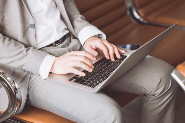特写商人在笔记本电脑上打字，坐在等候台上工作的无线概念。图片下载