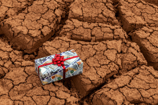 礼品盒上印着沙漠里干裂的粘土上的100美元钞票图片下载