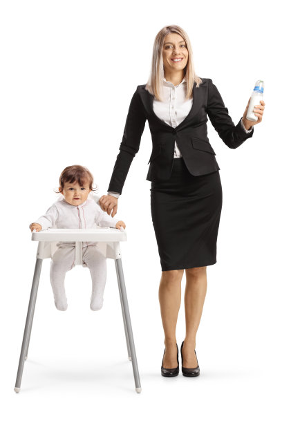 女商人拿着一瓶水，站在婴儿旁边，婴儿坐在白色背景的喂养椅上图片下载