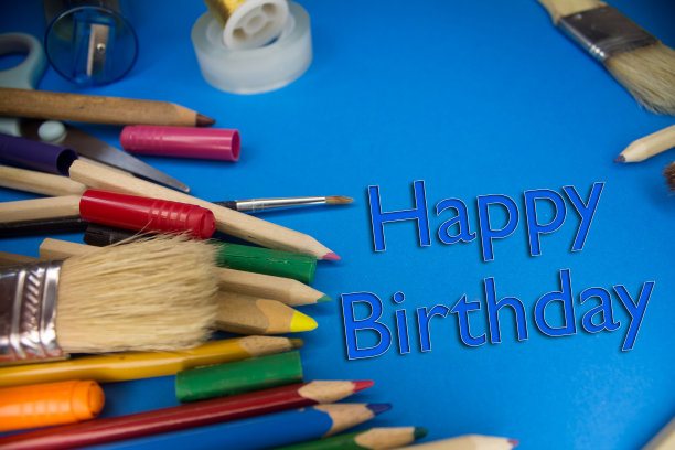 头顶上的学校用品，上面写着生日快乐的文字。画笔，铅笔，艺术工具。艺术和工艺工作工具。图片下载