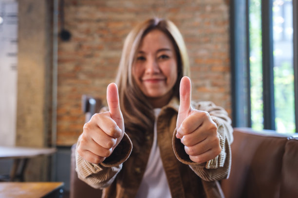 一个年轻的亚洲妇女做着竖起大拇指的手势图片下载