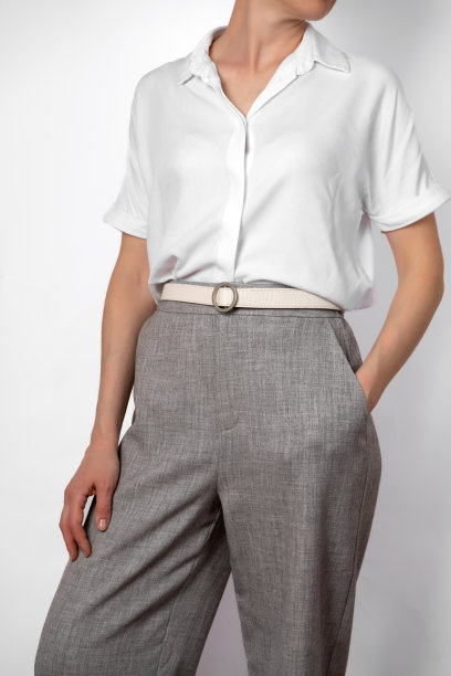 时尚女装休闲装。身穿白衬衫和灰色裤子的女子。用白色腰带。特写镜头。没脸，手插口袋，公事公办图片下载