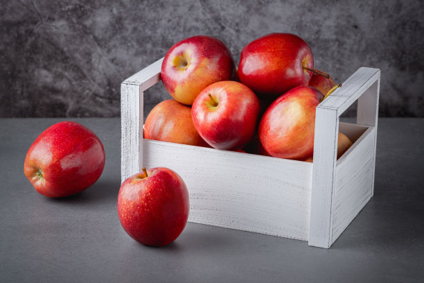 灰色背景的木箱里装着新鲜的红苹果。有机食品图片下载