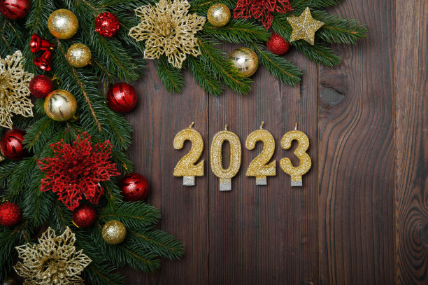 2023年新年快乐贺卡。蜡烛数字在木制背景和布局的圣诞树，球，礼物。关闭和复制空间，选择性聚焦..图片下载