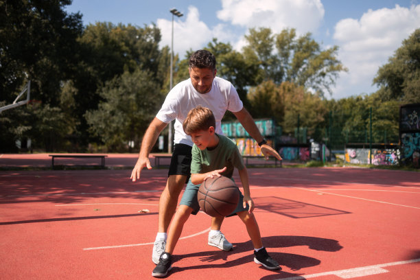 父子俩在公共篮球场打篮球。图片下载