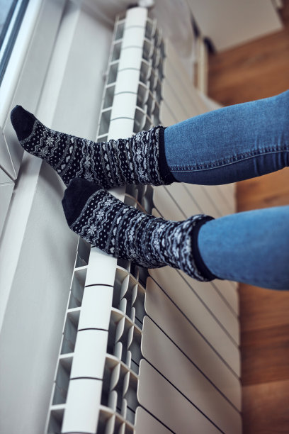 女人在寒冷的冬天给脚取暖，能源和煤气危机，寒冷的房间，供暖问题。图片下载