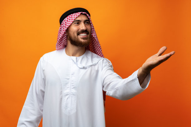 年轻的阿拉伯男子用手在橙色背景上复制空间图片下载