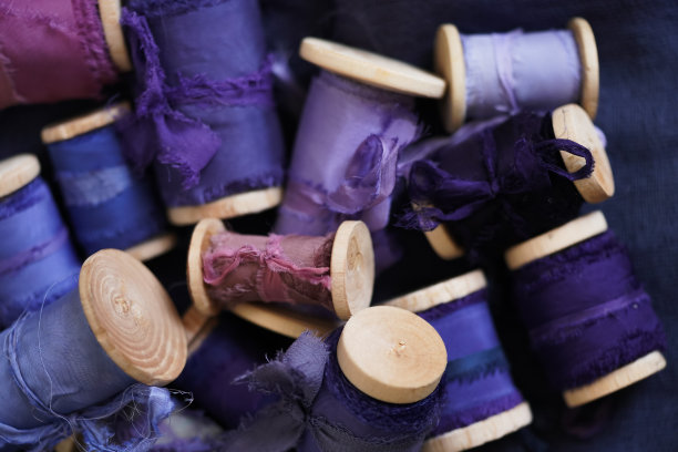特写许多不同主题的蓝色和紫色丝带在蓝色面料上蓝色背景图片下载