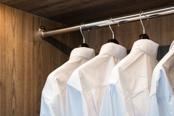 白色衬衫挂在木制衣柜的衣架上图片下载