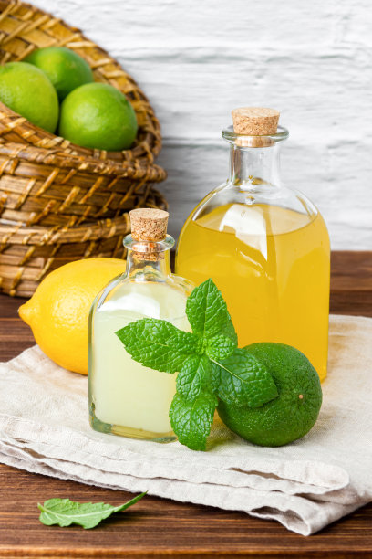 酸橙和柠檬糖浆装在玻璃瓶里，水果装在背景的篮子里图片下载