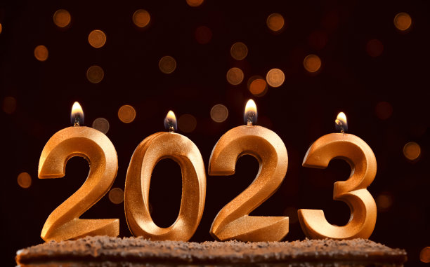 新年快乐。数字2023由金蜡烛制成。极简水平酒红色背景与明亮的黄色散景花环和空间的文字或设计。蜡烛随火燃烧。图片下载