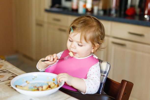 可爱的小女孩用勺子吃蔬菜泥和泥。食物、儿童、喂养和人的概念图片下载