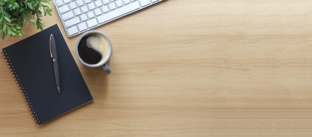 简单的办公场所，有无线键盘，笔记本和咖啡杯放在木桌上。顶部视图与复制空间为您的文本。图片下载