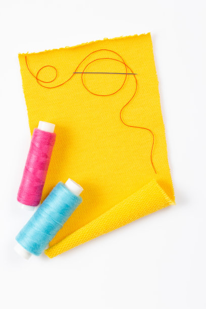 缝纫线和针与线轴在白色背景。一块织物的创意概念图片下载