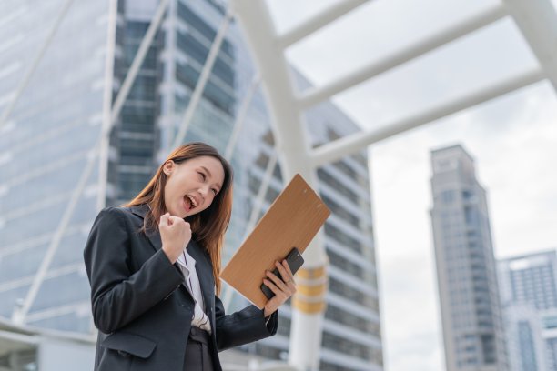 年轻迷人的亚洲职业女商人女士在曼谷市中心商业区阅读了最新的良好销售报告后欣喜若狂图片下载