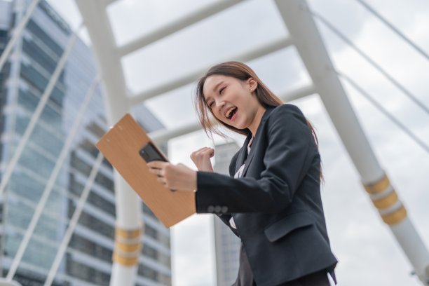 年轻迷人的亚洲职业女商人女士在曼谷市中心商业区阅读了最新的良好销售报告后欣喜若狂图片下载