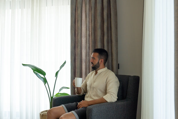 年轻人拿着杯子在房子的一个舒适的空间休息。图片下载