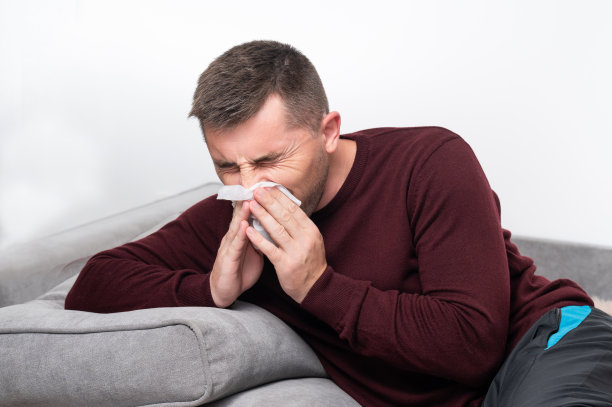 一个虚弱而疲惫的人用手帕擤鼻涕。图片下载