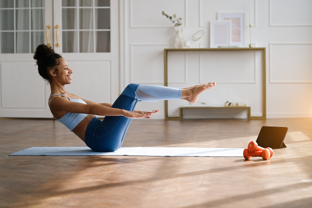 女子在客厅的瑜伽垫上练习图片下载
