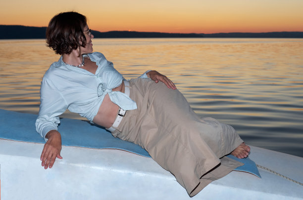 在放松的时刻。夏夜，躺在游艇上的女人图片下载