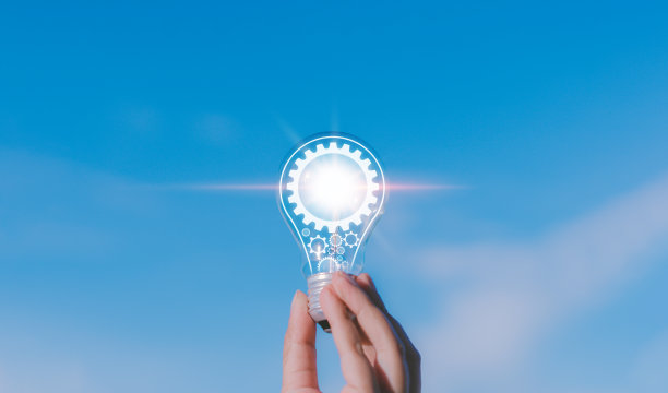 创意创新和灵感概念。手的人拿着照明灯泡与齿轮图标，与灯泡的创造力。天空背景下可持续商业发展的灵感图片下载