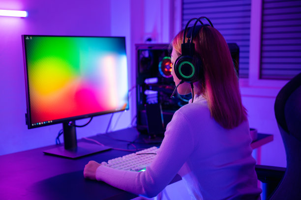 亚洲职业玩家在台式电脑上玩在线视频游戏，电脑上有五颜六色的霓虹LED灯图片下载