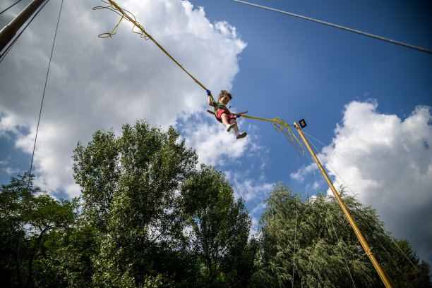 那个男孩正在蹦极蹦床上跳。有保险的孩子图片下载