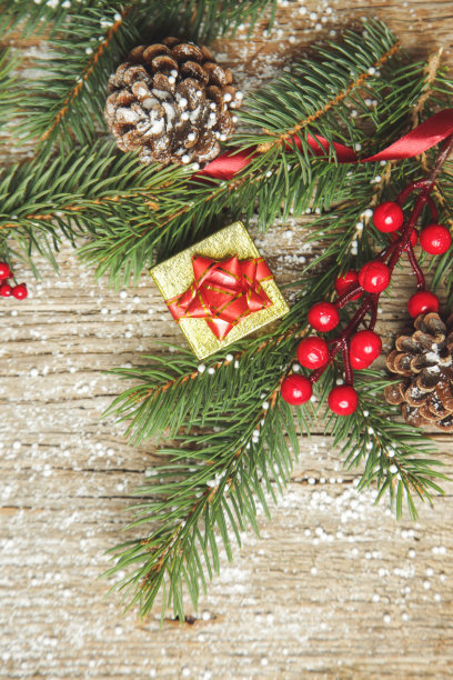 圣诞树的树枝，礼盒，针叶树球果和红色浆果顶视图复制空间在旧的木制背景。圣诞节，寒假，新年的概念。图片下载