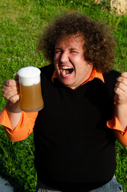 滑稽的胖子在街上喝啤酒。图片下载