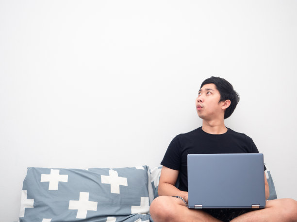 男人在床上用笔记本电脑感到兴奋，看着复制空间白色的背景图片下载