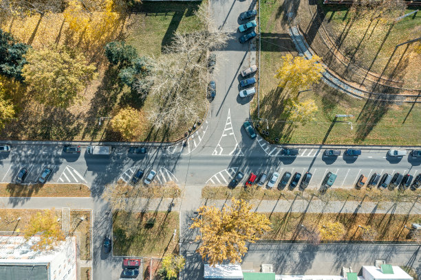 室外停车场，车停在秋天的黄树中间。空中俯视图。图片下载